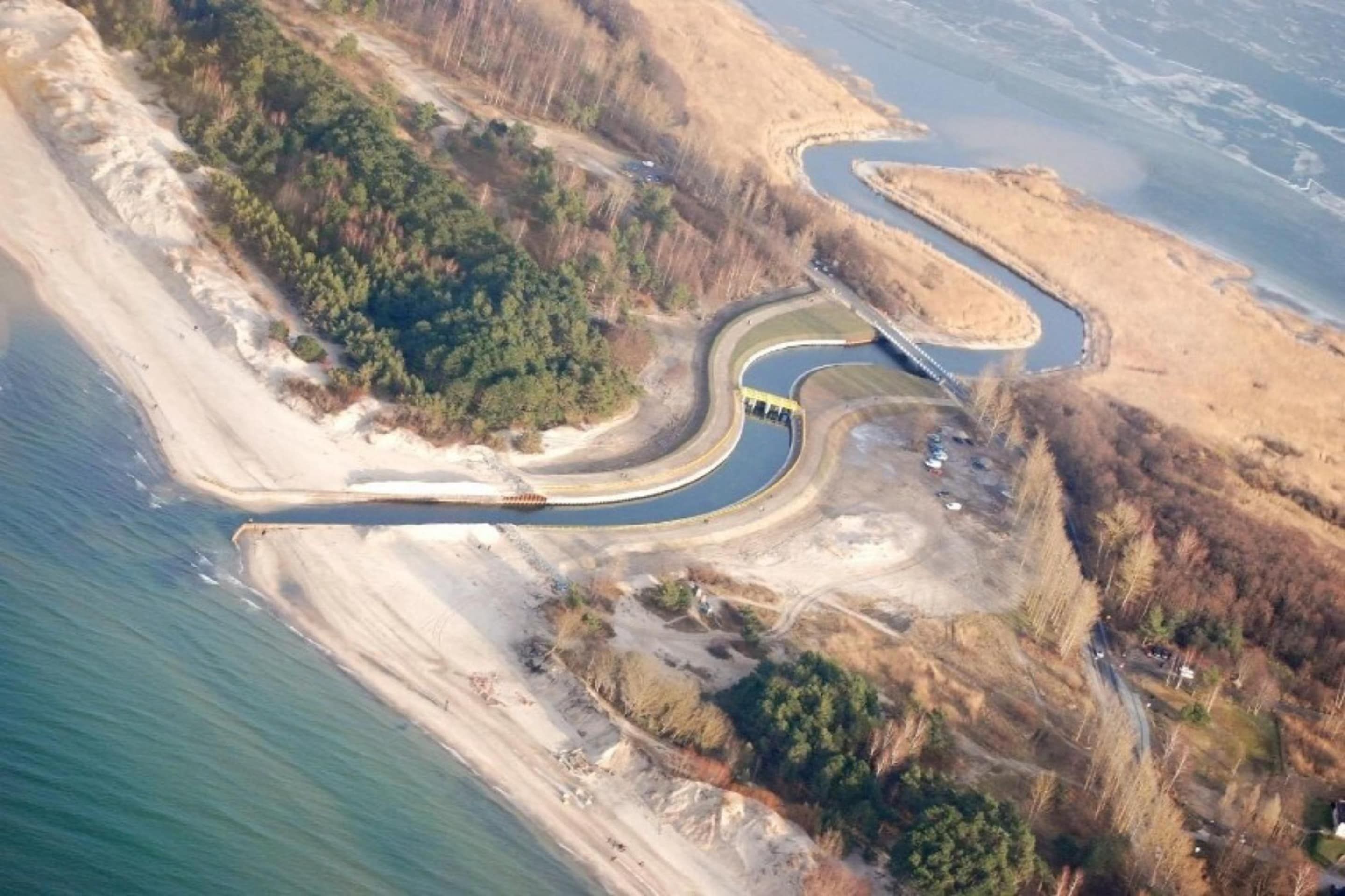 Vista aérea de una zona costera con una carretera sinuosa, un puente y una playa.