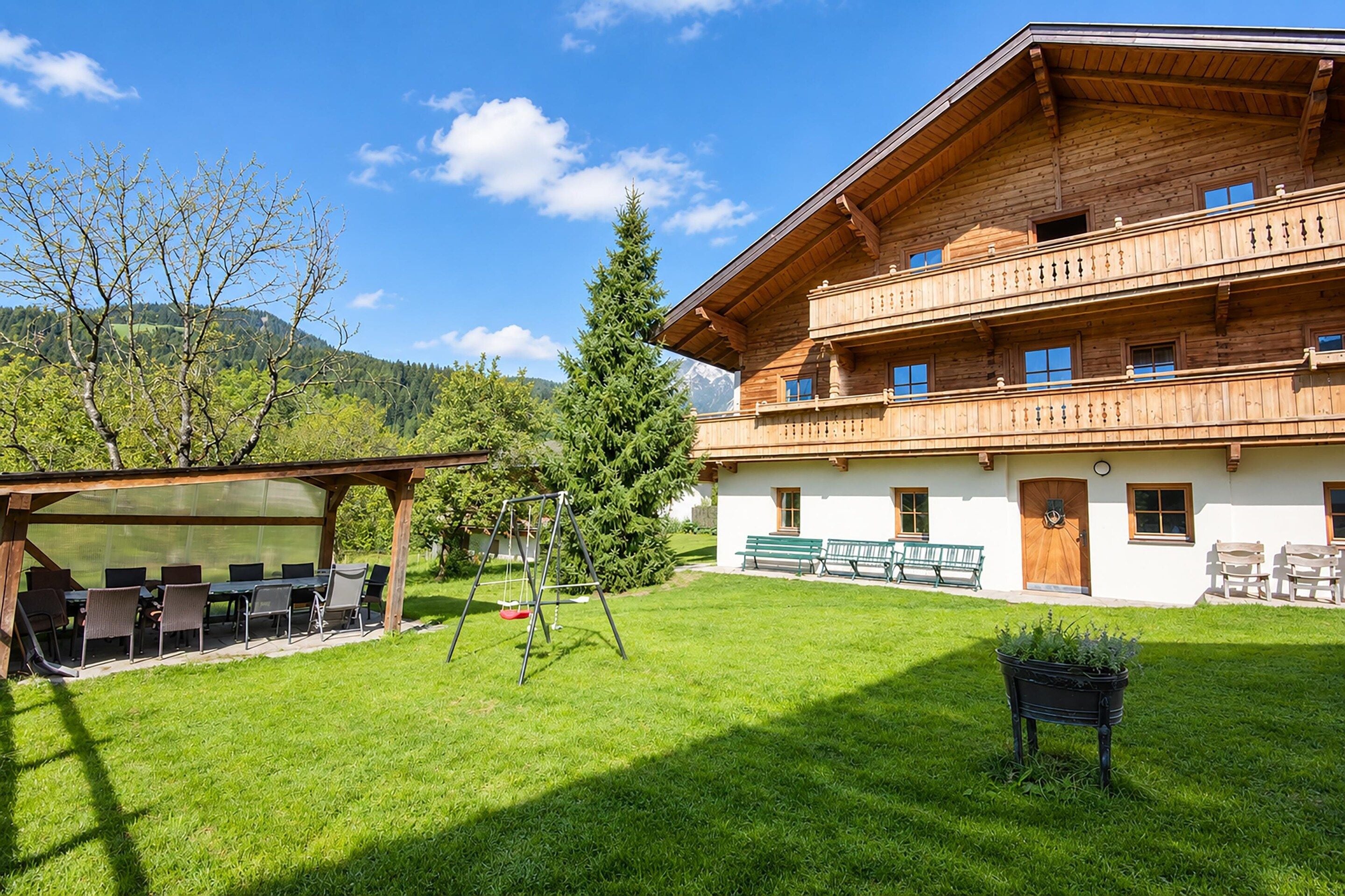 A two-story wooden building with a balcony, a covered outdoor seating area, and a well-maintained lawn.