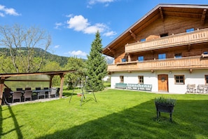 A two-story wooden building with a balcony, a covered outdoor seating area, and a well-maintained lawn.