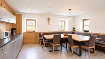 A modern kitchen with wooden cabinets, a built-in microwave, and a dining area with a wooden table and chairs.