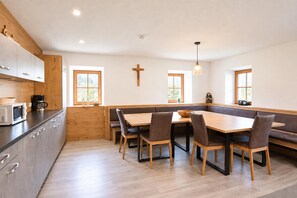 A modern kitchen with wooden cabinets, a built-in microwave, and a dining area with a wooden table and chairs. - Farmhouse in Soll Near Wilder Kaiser Ski Area (Soell)