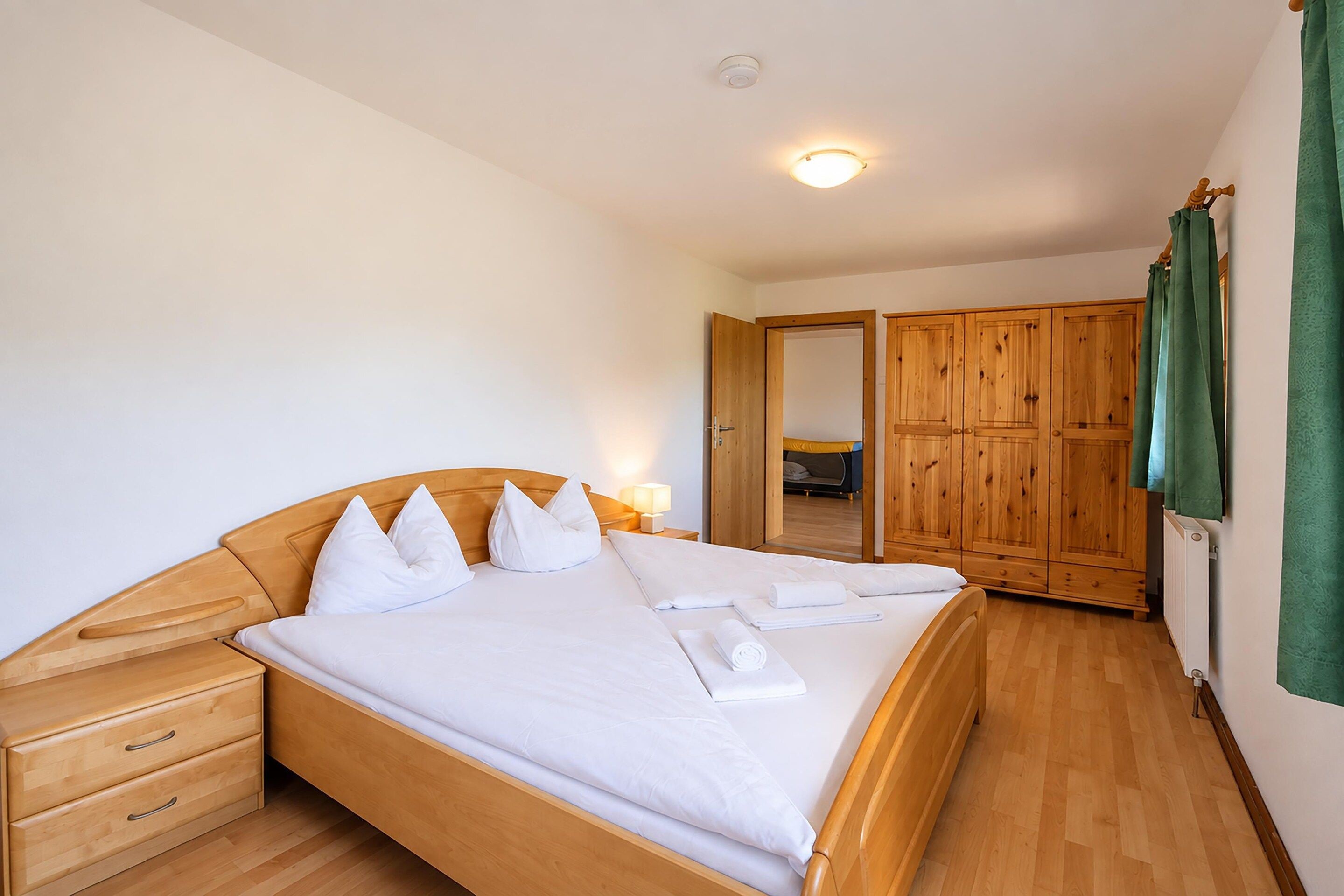 A bedroom with a wooden bed, a nightstand, a dresser, and a wardrobe.