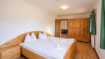 A bedroom with a wooden bed, a nightstand, a dresser, and a wardrobe.