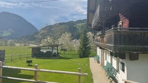 Un chalet traditionnel doté d’un balcon, d’un petit jardin et ayant une montagne en toile de fond.