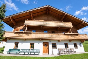 A two-story wooden chalet with balconies, a front door, and a bench outside. - Farmhouse in Soll Near Wilder Kaiser Ski Area (Soell)