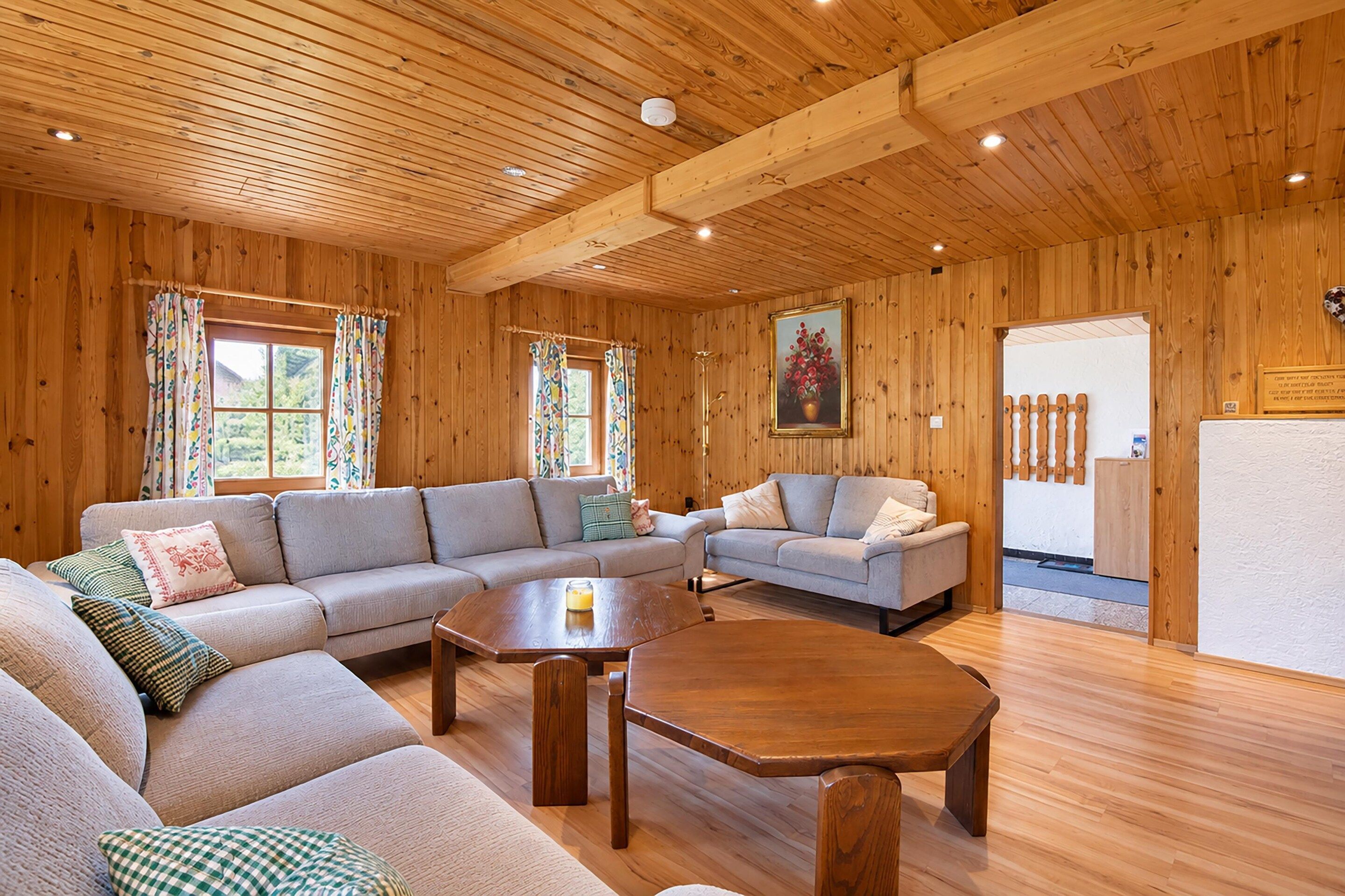 A wooden interior with a sofa, armchairs, a coffee table, and a painting on the wall.