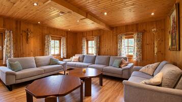 A wooden interior with a sofa set, a coffee table, and a painting on the wall.