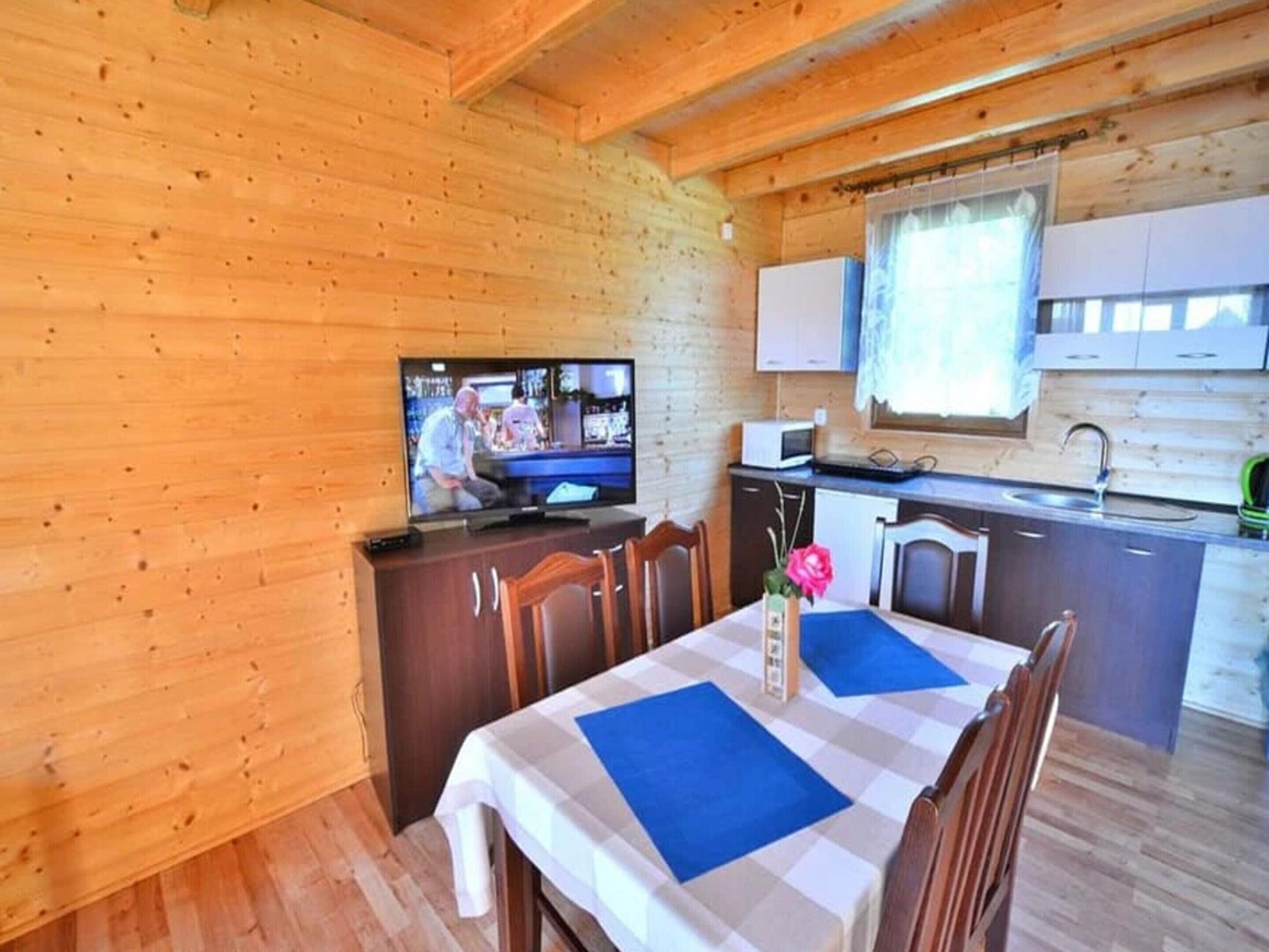 A cozy cabin interior with a dining area, a kitchen, and a television.