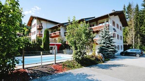 Ein Hotel mit mehreren Balkonen, einem Schwimmbad und einem geparkten Auto davor.
