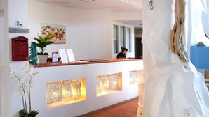 A reception desk with a receptionist, a horse-themed painting, a red mailbox, and decorative panels. - Apartment in Holiday Complex Only 100 m From the Beach (Golfo Aranci)