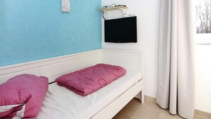 A room with a single bed, a mounted TV, and a window with curtains. - Ferienhaus, Boiensdorf (Boiensdorf)
