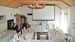 Ein Essbereich mit weißen Tischen und Stühlen, einem Kamin aus Ziegelsteinen und einer Chandelier.