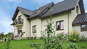 Ein zweistöckiges Haus mit Balkon und Garten, bewölkter Himmel.