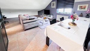 Ein modernes Wohnzimmer mit einer Couch, einem Esstisch und einem Fernseher.