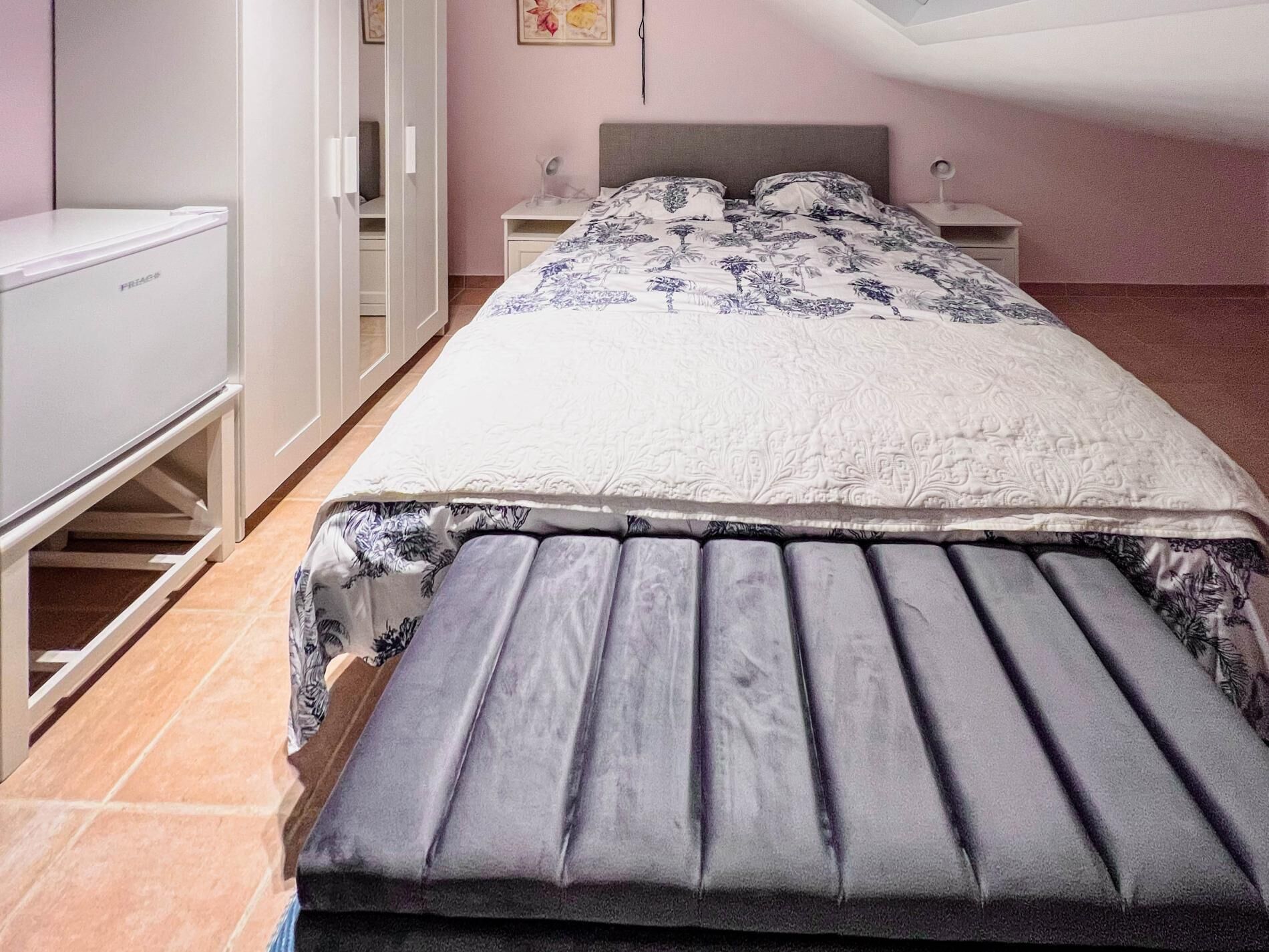 A bedroom with a bed, a desk, and a wardrobe.