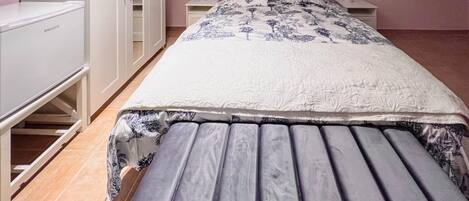 A bedroom with a bed, a desk, and a wardrobe.