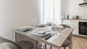 A modern kitchen with a dining table set for four, including plates, glasses, and cutlery. - Italianway Comfort - Boscovich 23 (Milan)
