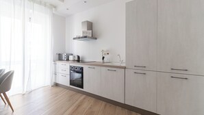 A modern kitchen with light wood cabinets, a built-in oven, and a stainless steel range hood. - Italianway Comfort - Boscovich 23 (Milan)