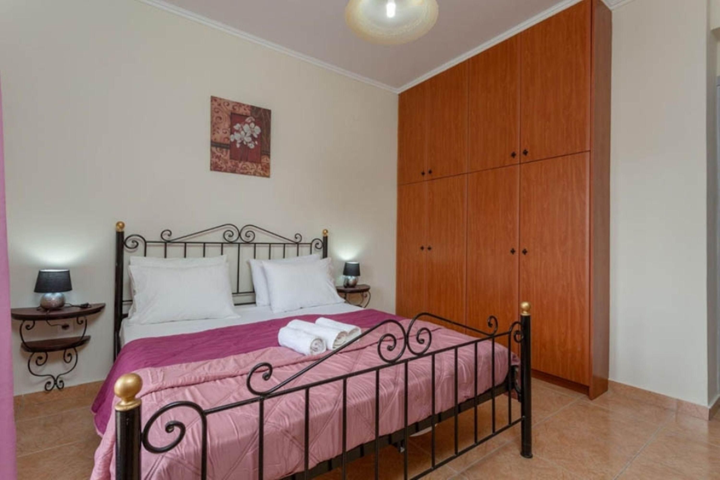 A bedroom with a bed, wooden wardrobe, and a wall-mounted artwork.