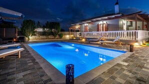Une piscine dotée de chaises longues et d’un espace abrité avec une rambarde.