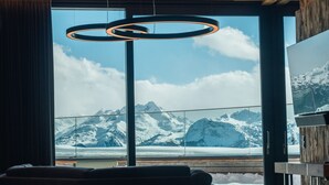 En modern inredning med ett stort fönster som bjuder på en utsikt över snöklädda berg.