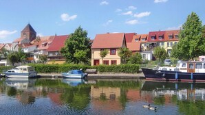 Ein Kanal mit Booten, einer Ente und Gebäuden mit roten Dächern.