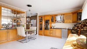 Una cocina amplia con armarios de madera, un comedor con mesa y sillas, y un gran ventanal que proporciona luz natural.