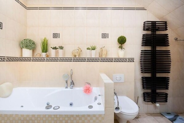 A bathroom with a bathtub, toilet, and a towel rack. - Holiday Apartment, Pool, Close to Beach, Rewal (Rewal)