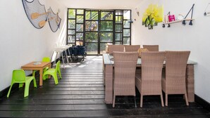 Un espacio interior moderno con mobiliario de mimbre, una mesa de madera y sillas de color verde brillante.