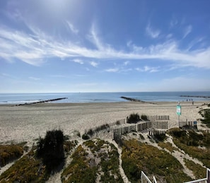 A beach with a wooden fence and a sign, under a clear sky.