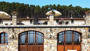 Un edificio in pietra con finestre ad arco e un balcone con ombrelloni.