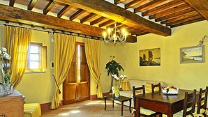 Zona pranzo con tavolo e sedie in legno, un divano e un lampadario.