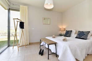 A bedroom with a bed, bedside table, lamp, and a view of the outdoors. - Holiday Home With Pool on Golf Resort, Maspalomas (San Bartolomé de Tirajana)