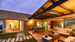 A modern outdoor living area with a dining set, seating, and a stone wall. - Holiday Home With Pool on Golf Resort, Maspalomas (San Bartolomé de Tirajana)