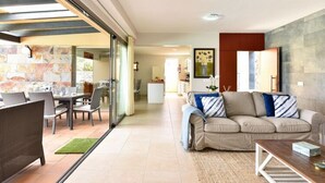 A modern living room with a sofa, a coffee table, and a dining area with chairs and a table. - Holiday Home With Pool on Golf Resort, Maspalomas (San Bartolomé de Tirajana)