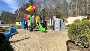 A playground with various play structures including slides and climbing areas, surrounded by sand and greenery. - Single-story Holiday Homes Very Close to the Beach (gmina Sianów)