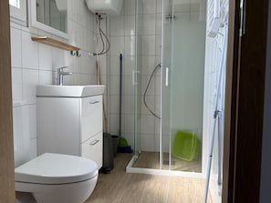 Casa de banho moderna com sanita, lavatório e cabine de duche em vidro.