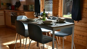 A wooden cabin interior with a dining table set for four, surrounded by chairs.