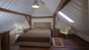 Ein Schlafzimmer mit einem großen Bett, zwei Nachttischen, einem Sessel und einem Oberlicht.