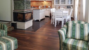 Ein geräumiges Wohnzimmer mit Kamin, ein Essbereich mit weißer Möbel und eine Küche mit Holzschränken und einer gefliesten Spritzschutzleiste.