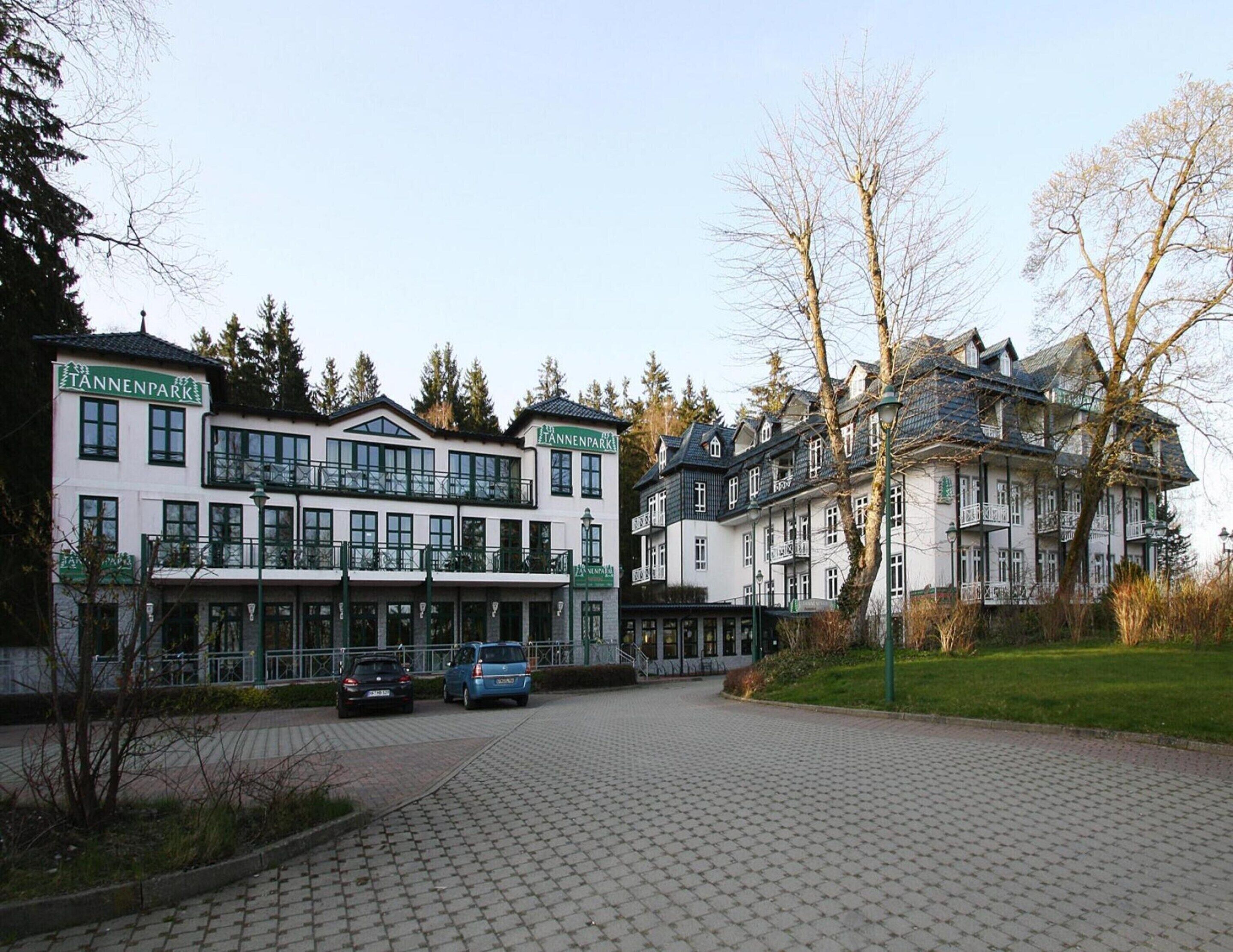 Un hotel con fachada blanca, balcones y un acceso empedrado.