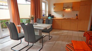 A modern kitchen with wooden cabinets, a dining table with chairs, and a view of the outdoors. - Appartementhaus Nicole, Zinnowitz (Zinnowitz)