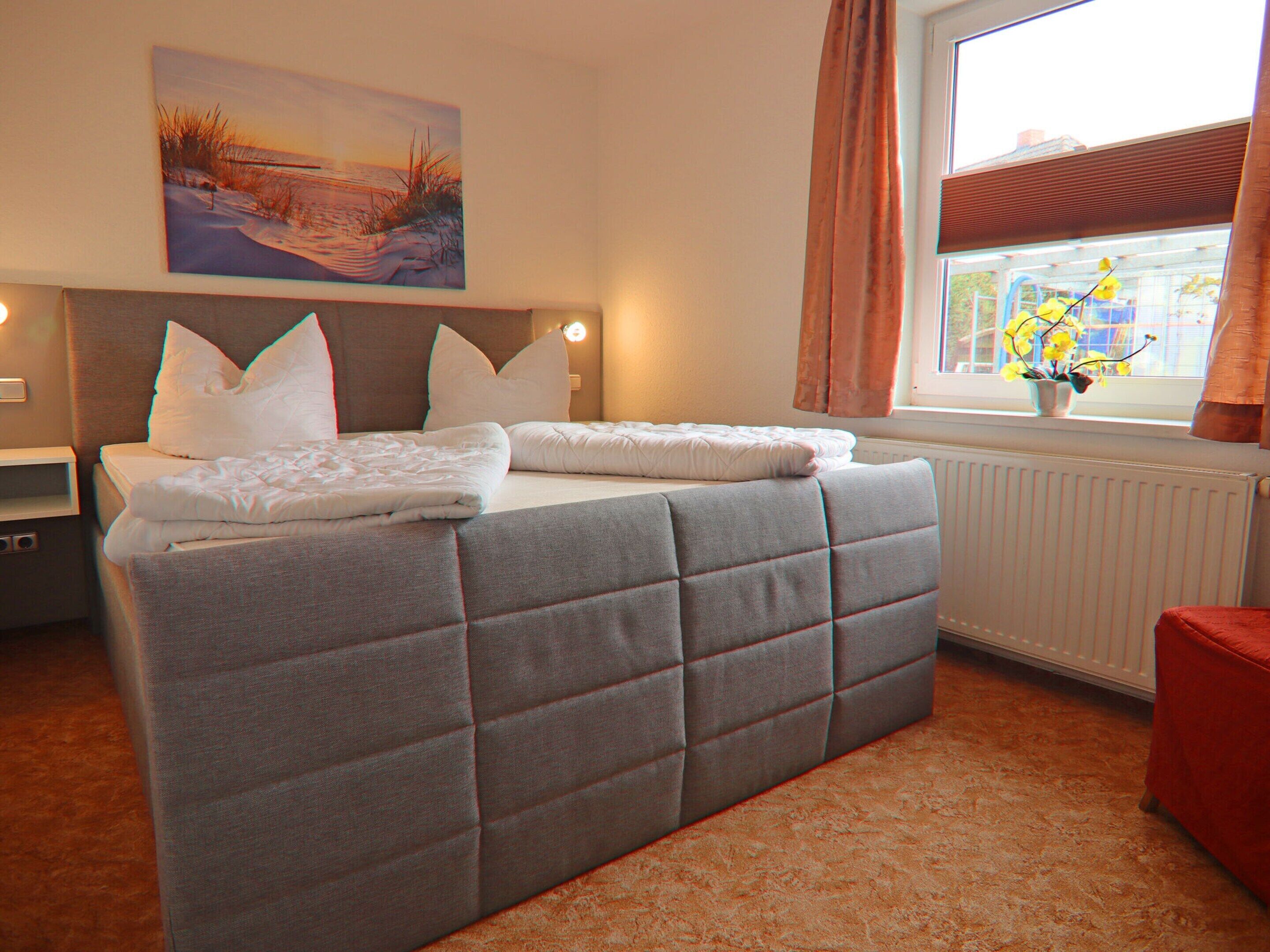 Une chambre à coucher avec un grand lit, une table de chevet, une fenêtre avec des rideaux et un tableau au mur.