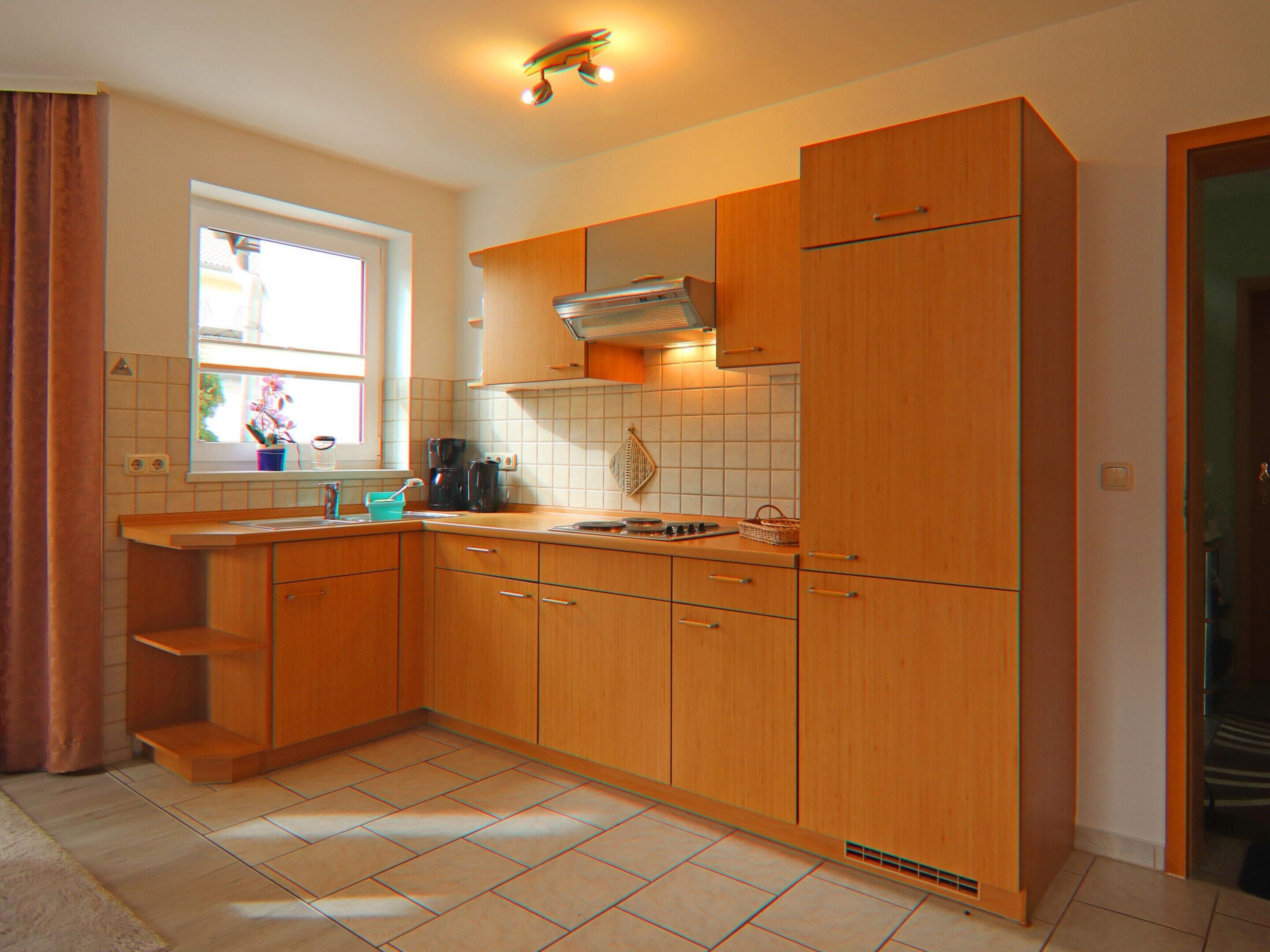 A compact kitchen with wooden cabinets, a window, and a built-in stove.