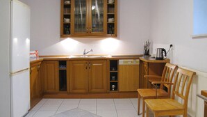 Une cuisine de taille réduite, dotée de meubles en bois, d’un réfrigérateur blanc, d’un évier et d’un lave-vaisselle.