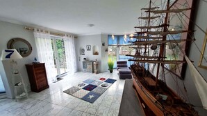 A spacious living room with a large ship model, a sofa, a coffee table, and a patterned rug. - Charmante Hausvilla in Bojendorf (Fehmarn)