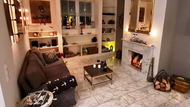 Ein Wohnzimmer mit Kamin, einer Couch, einem Couchtisch und einem Bücherregal.