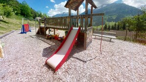 A playground with a slide, climbing area, and a wooden structure with a roof. - Chalet in Wildkogel Near Ski Slopes (Neukirchen am Grossvenediger)