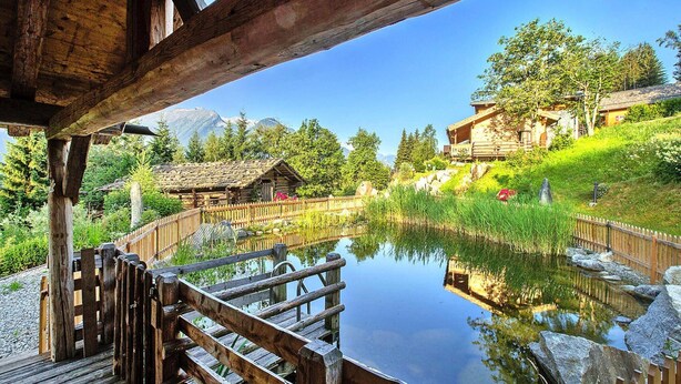 A wooden deck overlooking a pond with a mountain backdrop. - Chalet in Wildkogel Near Ski Slopes (Neukirchen am Grossvenediger)