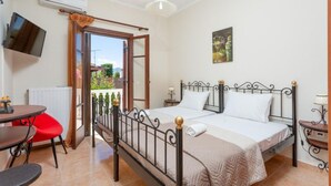 A bedroom with a bed, a TV mounted on the wall, a window with curtains, and a radiator. - Villa Mansion With Private Pool (Zakynthos)